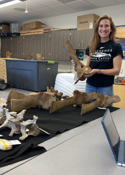 Jamie smiling while holding a vertebrae in a lab setting.