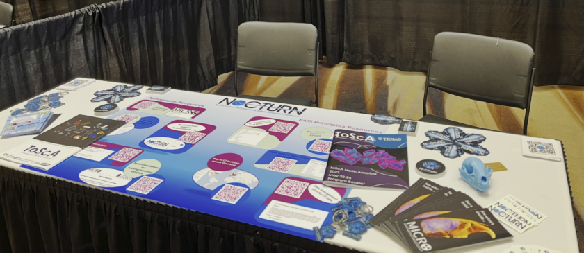 Photo of a table top covered with CT-related conference programs, stickers, and QR codes.