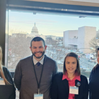 Photograph of four people in a line. From left to right: Morgan Chase, Paul Gignac, Jaimi Gray, and JJ Hill with the Capitol Building in the background.