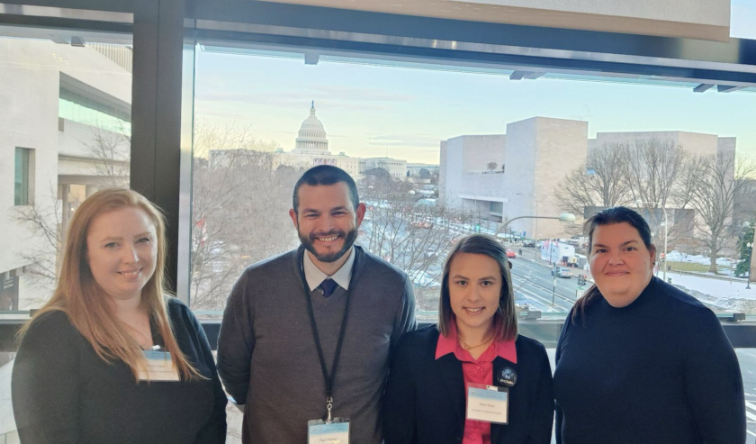 Photograph of four people in a line. From left to right: Morgan Chase, Paul Gignac, Jaimi Gray, and JJ Hill with the Capitol Building in the background.